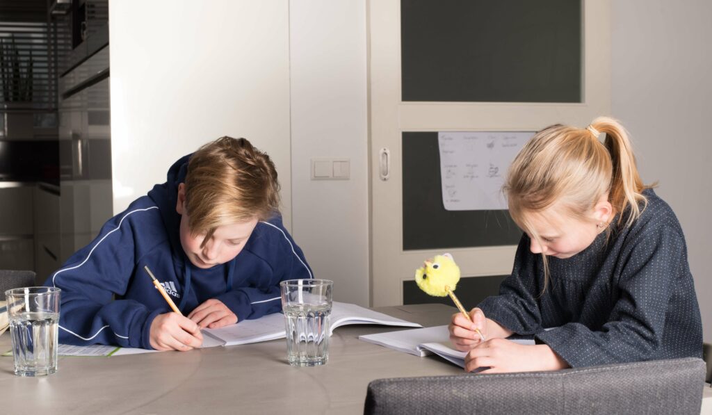 Kinderen maken huiswerk aan eettafel
