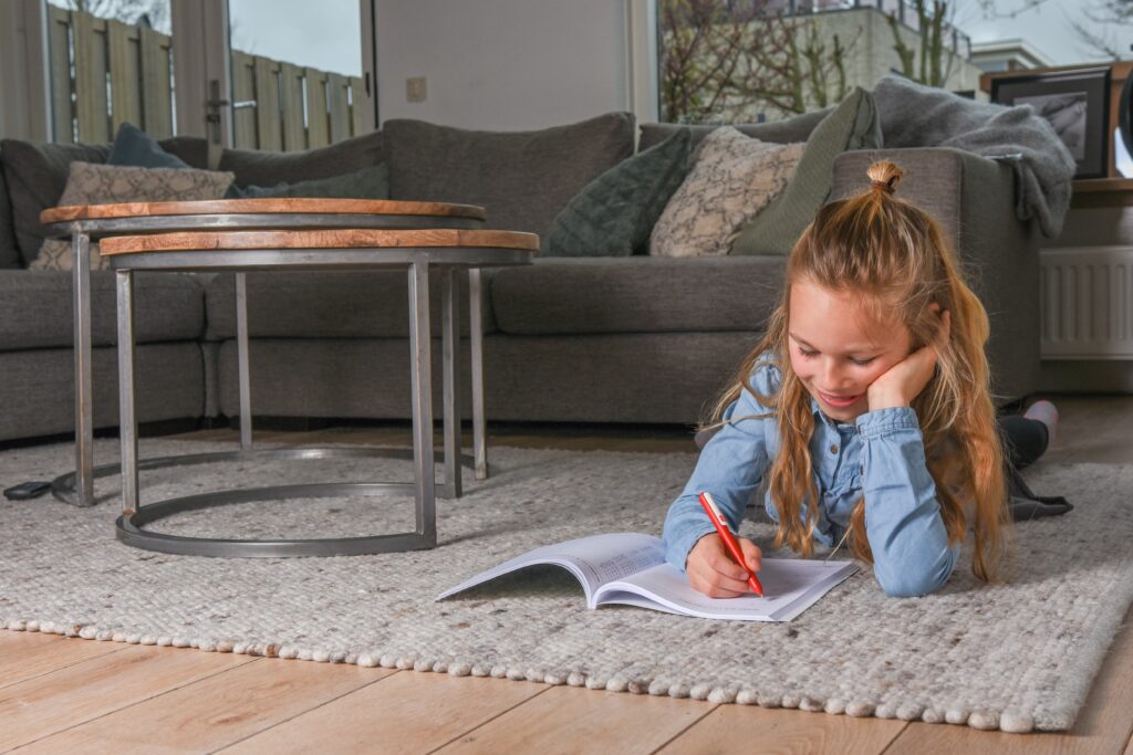 Meisje schrijft op de grond in boek