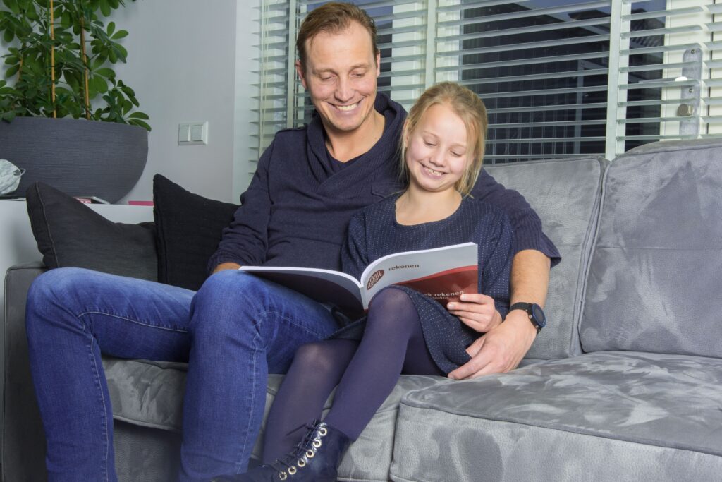 vader en dochter met oefenboek op de bank