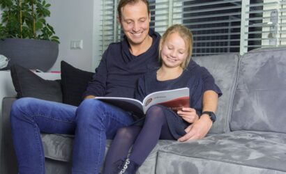 vader en dochter met oefenboek op de bank