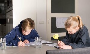 broer en zus maken schoolopdrachten aan tafel