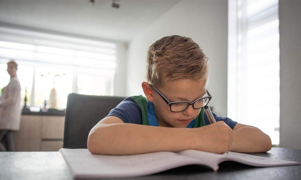 jongetje maakt school opdrachten in de keuken
