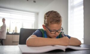 jongetje maakt school opdrachten in de keuken