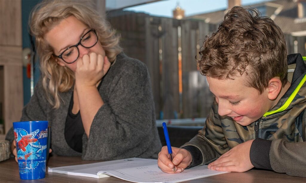 moeder helpt zoon met oefeningen in werkboek