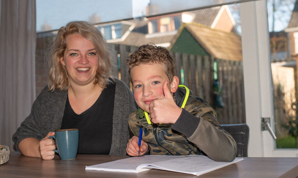 moeder helpt zoon met schoolopdrachten aan tafel