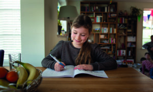 meisje maakt huiswerk aan keukentafel