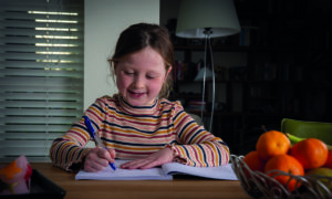 meisje aan tafel met pen in hand maakt opdrachten