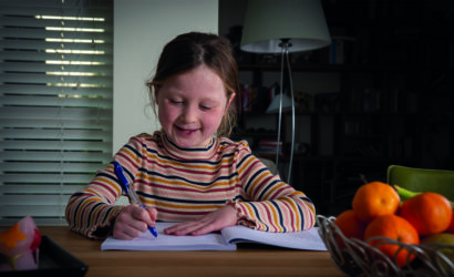 meisje aan tafel met pen in hand maakt opdrachten