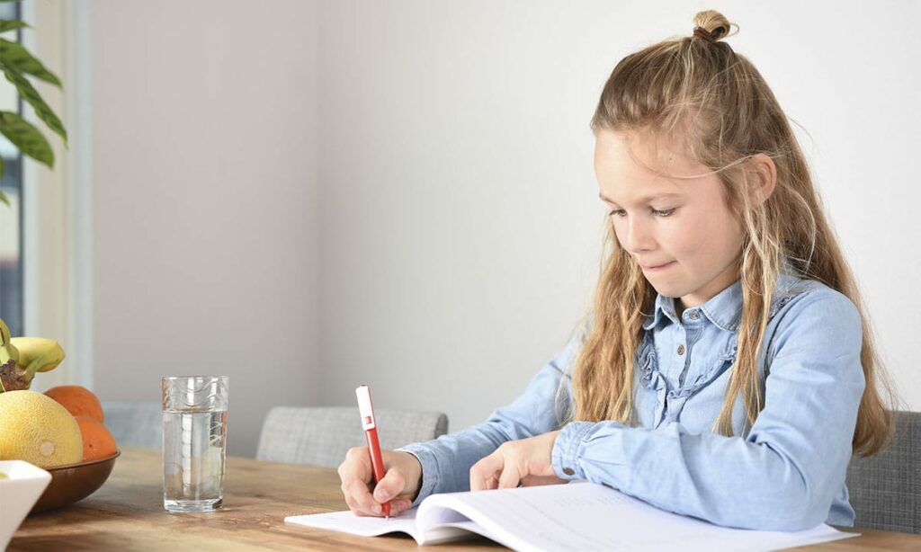 meisje ijverig aan het werk in werkboek aan tafel