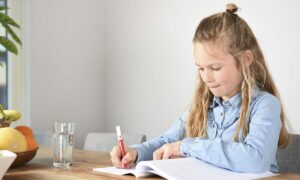 meisje ijverig aan het werk in werkboek aan tafel