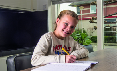 meisje maakt opdrachten in werkboek aan de keukentafel