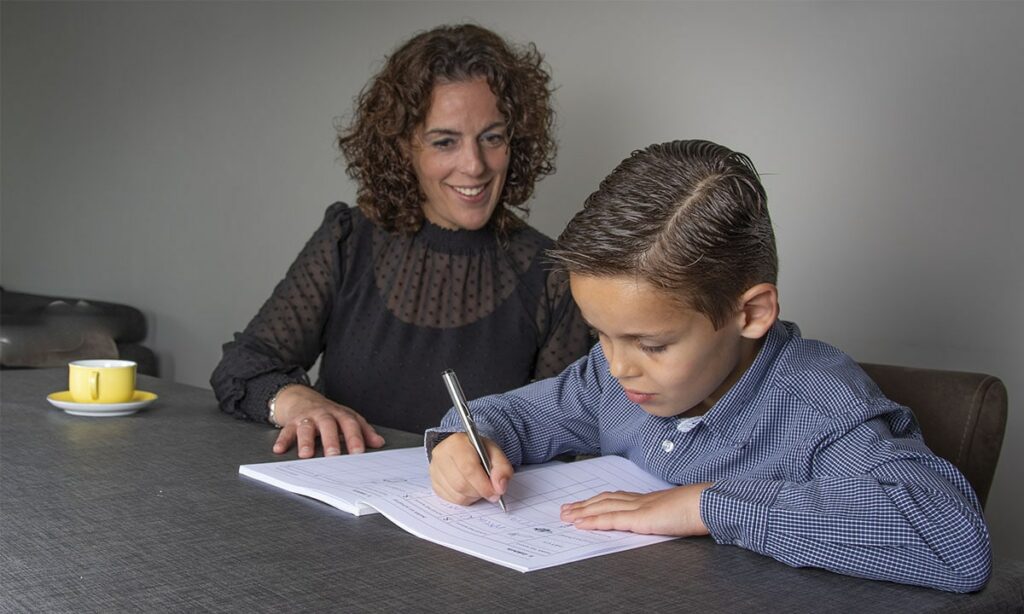 moeder en zoon aan tafel schrijven in oefenboek