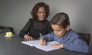 moeder en zoon aan tafel schrijven in oefenboek