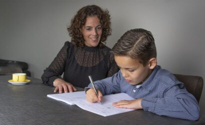 moeder en zoon aan tafel schrijven in oefenboek