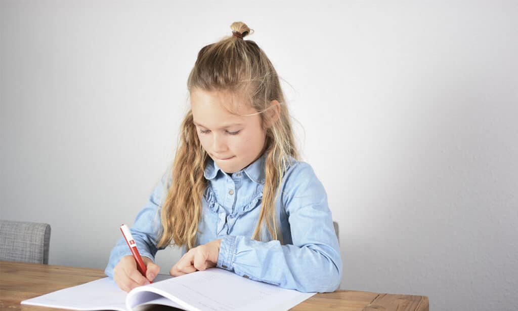 meisje werkt geconcentreerd in werkboek