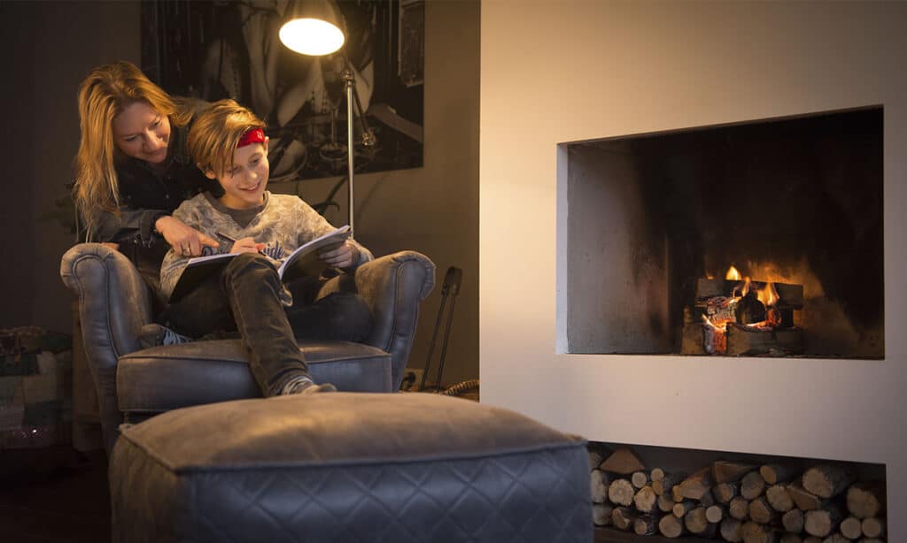 moeder en zoon in fauteuil voor de open haard leren uit werkboek
