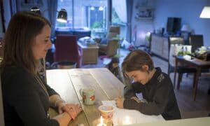 moeder helpt kind met oefeningen uit een werkboek