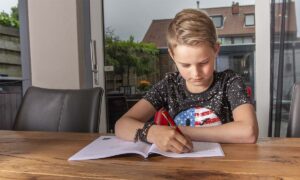 jongen maakt opdrachten aan tafel in werkboek